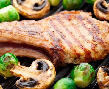 bone in pork chop on a plate with mushrooms and brussels sprouts