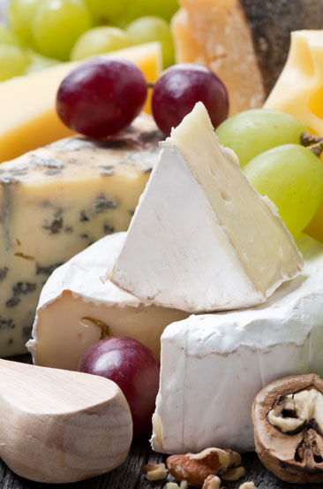 a collection of soft cheese wheels with grapes and nuts